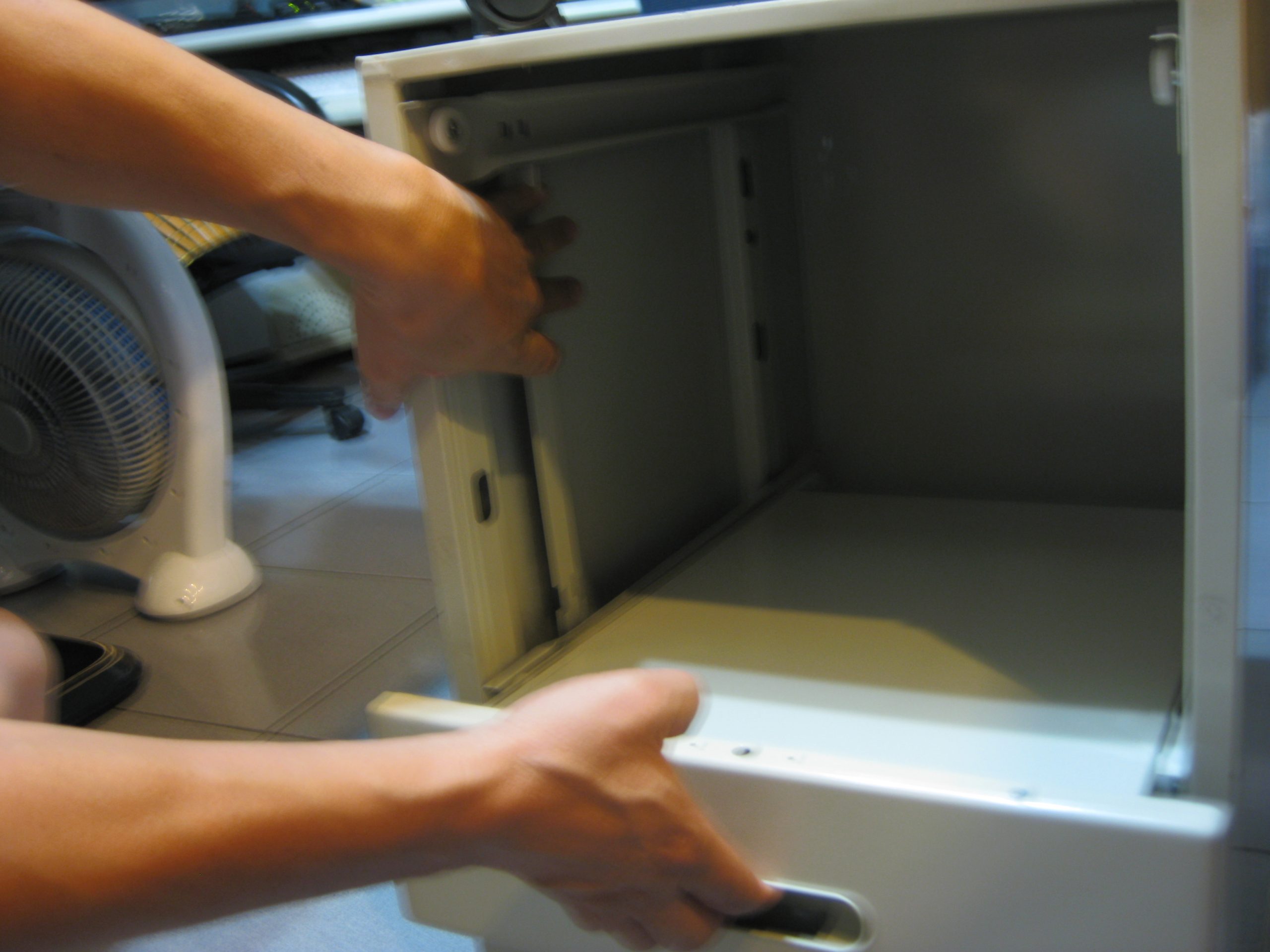 活動櫃,袖箱左手將連桿上提，右手將第二層抽屜拉出