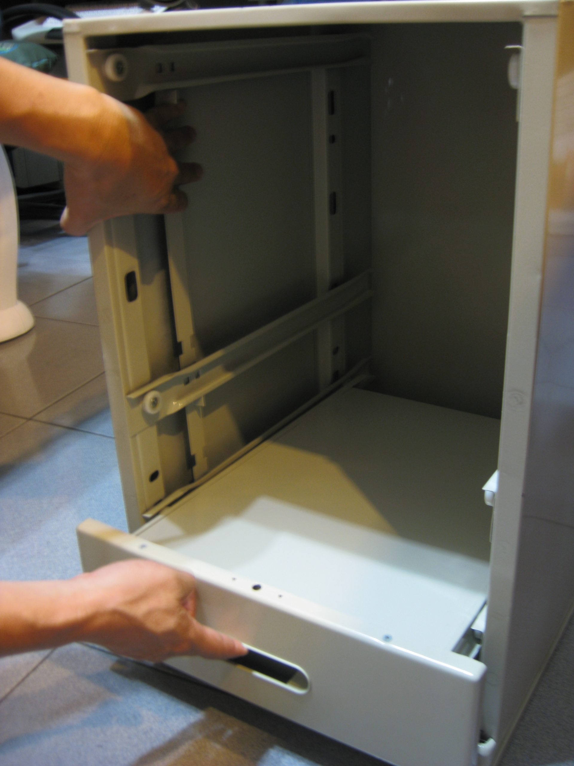 活動櫃,袖箱左手將連桿上提，右手將第一層抽屜拉出抽屜全部拉出